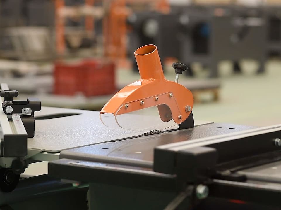Esquadrejadeira Smartmaq com a coifa laranja sobre a mesa de corte